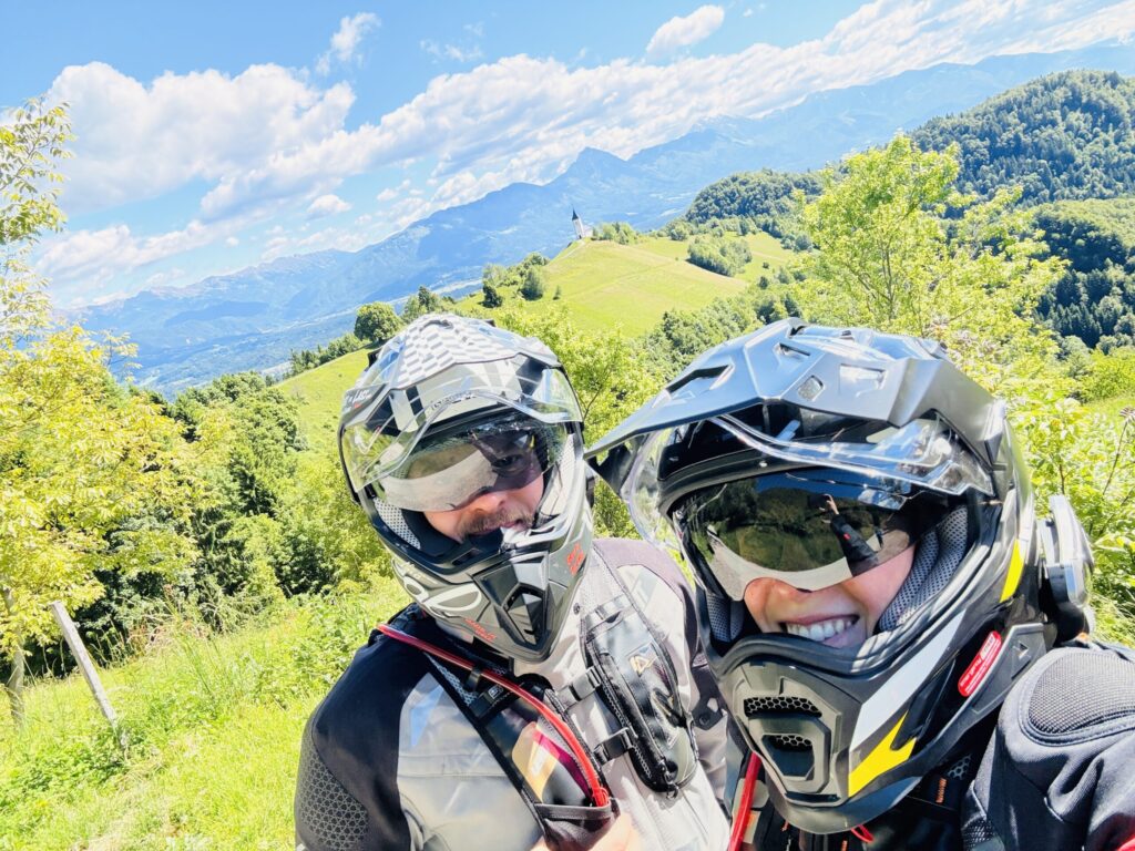 Two Motos & Wonders riders in front of alpine hills and mountain panorama