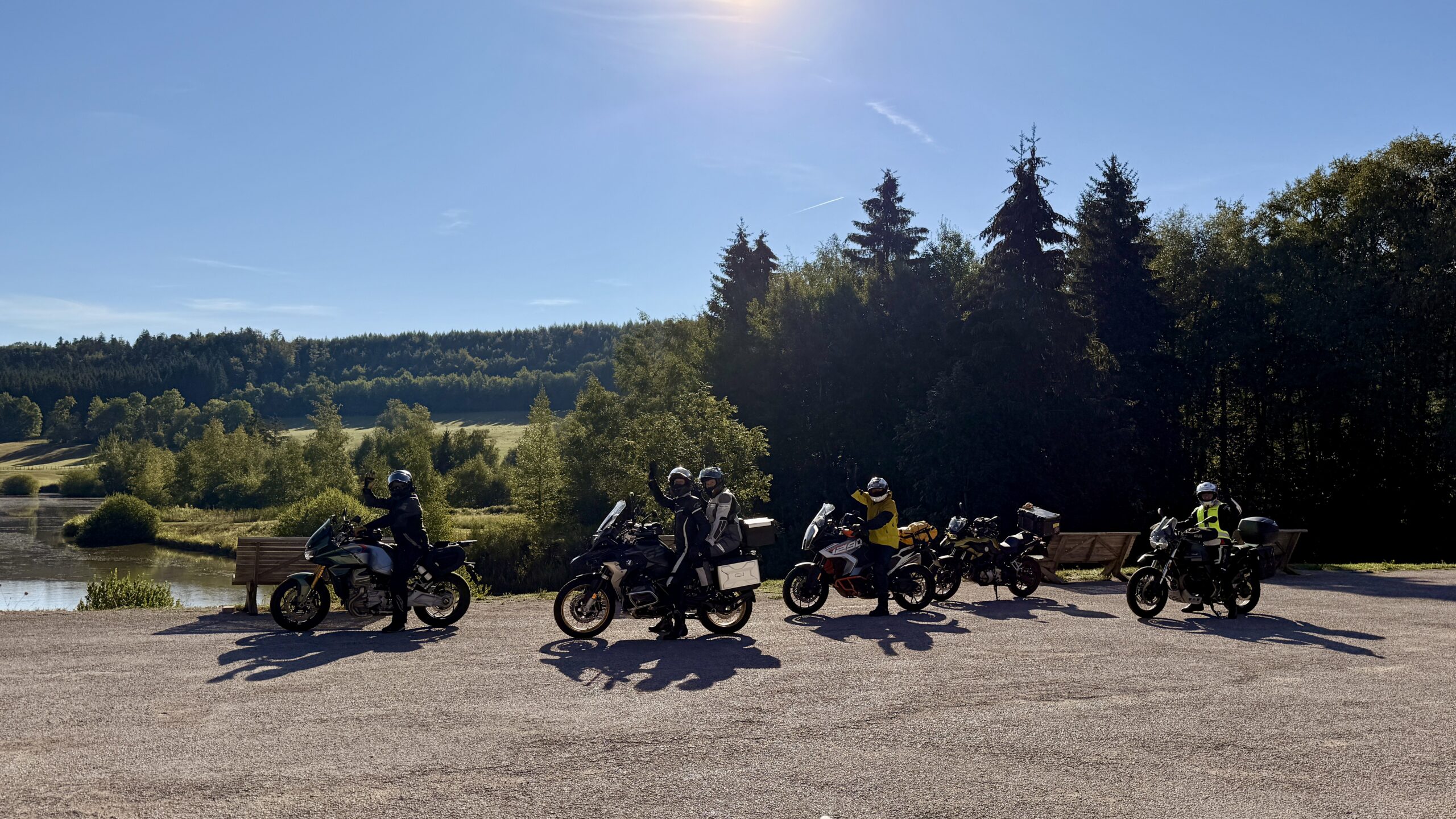 Motorradgruppe beim Fotostopp an einem Weiher im Jura