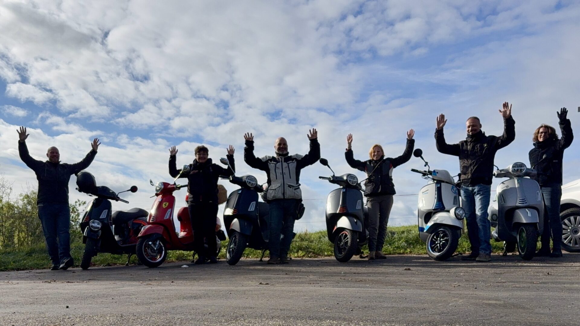 Vespa-Gruppe von Motos & Wonders jubelt mit erhobenen Armen bei den Rollern auf der Lüderenalp