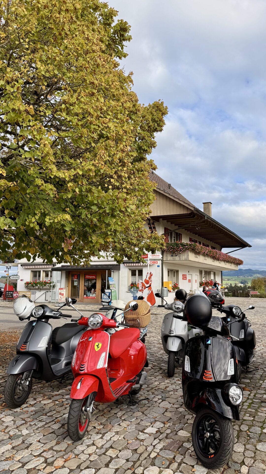 Vespas auf dem Kopfsteinpflaster vor einem Dorfgebäude im Emmental